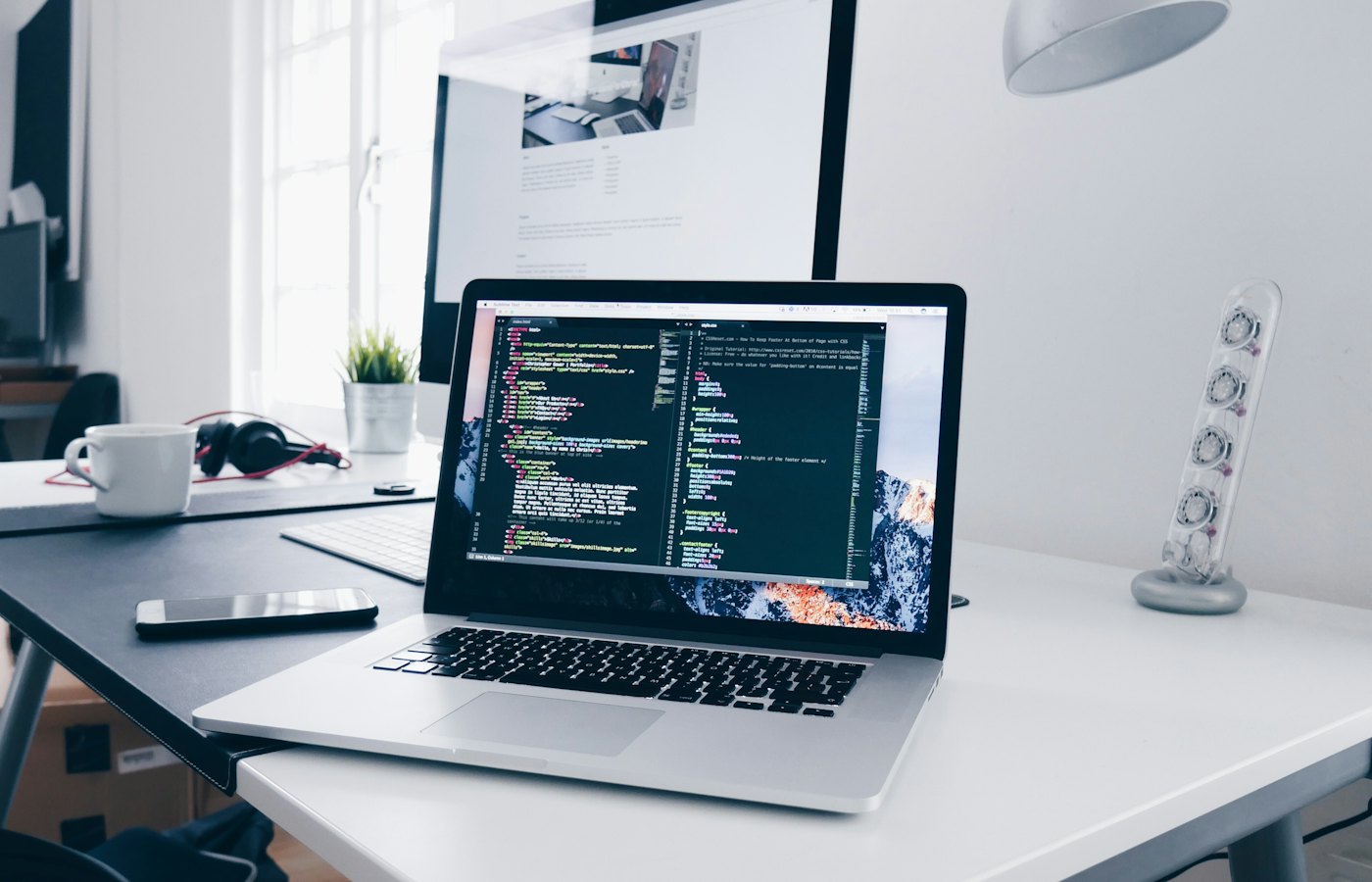 Laptop showing website code on a designer's desk